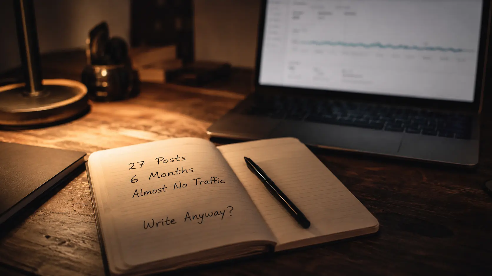 Notebook showing "27 Posts, 6 Months, Almost No Traffic" beside a laptop displaying analytics, representing a blogging journey and low blog traffic experience.